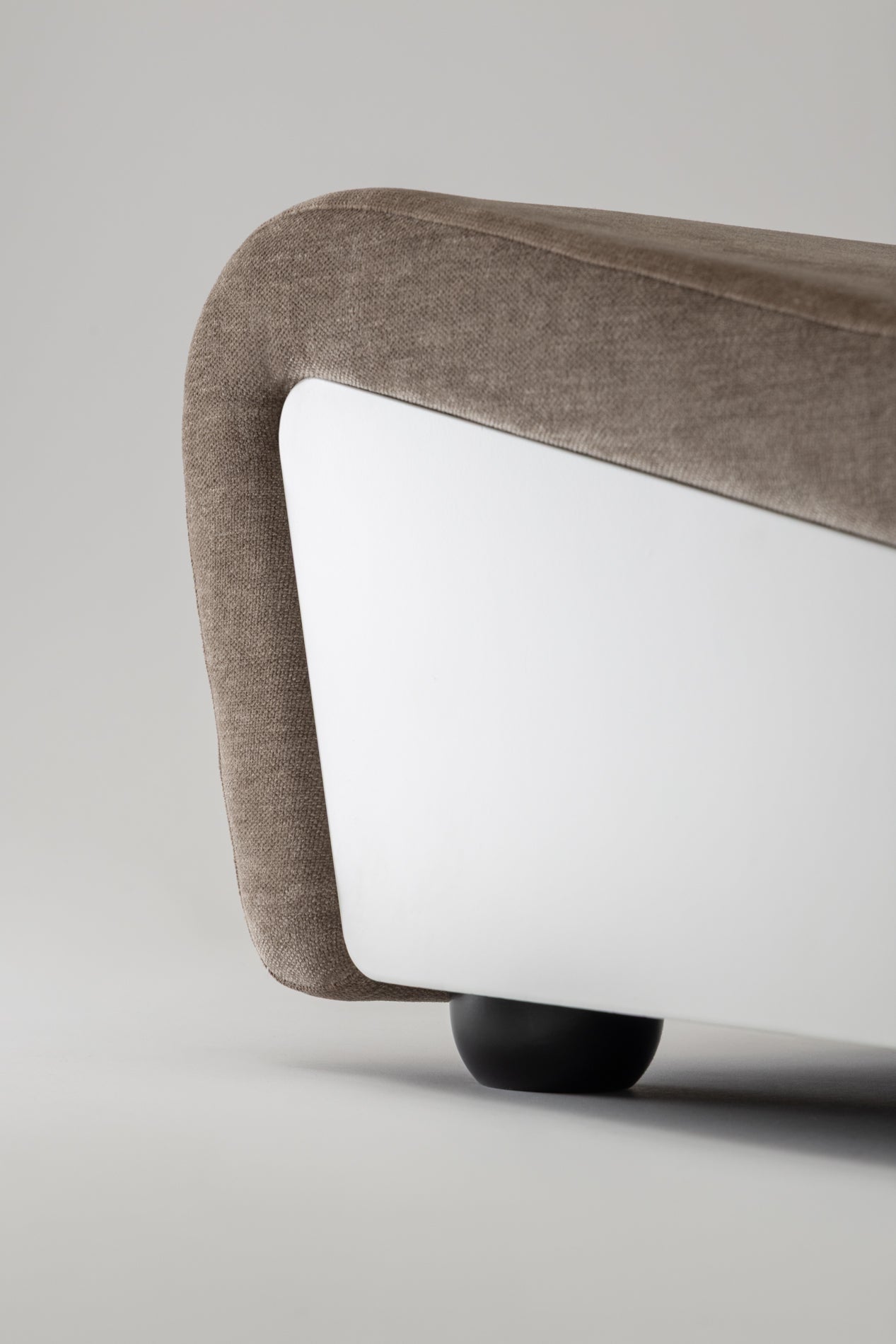 Close-up of the Dialogue lounge chair in Clay grey fabric with white lacquered wood side panels