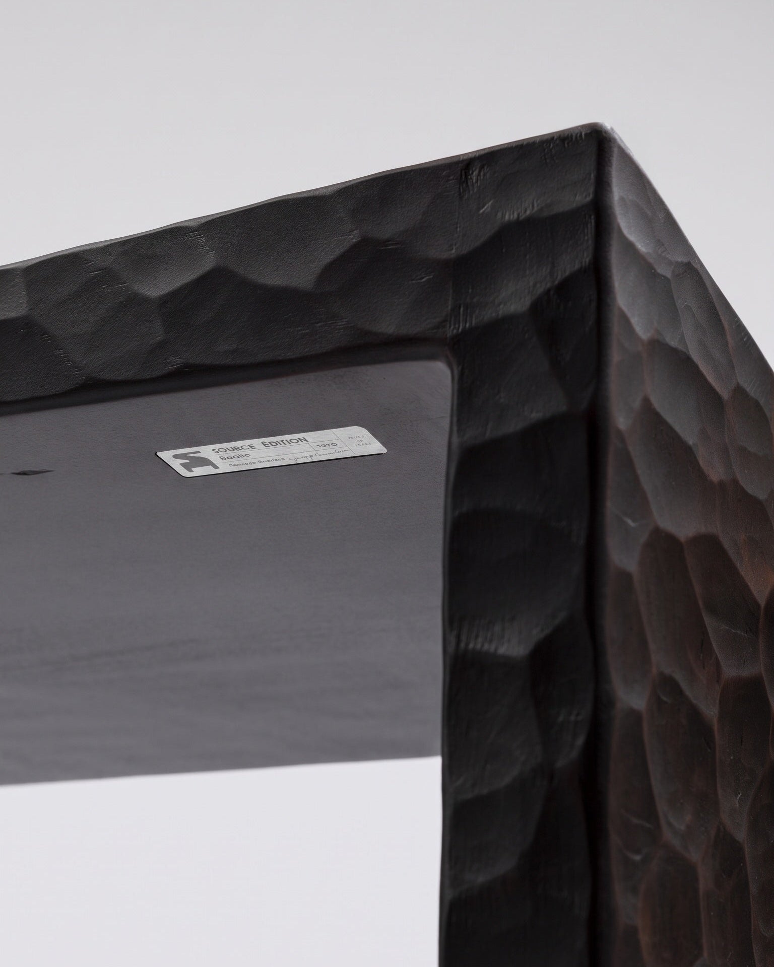 Authenticity plaque and close-up of the Basilio stool in solid linden wood with unique dark gouged finish 