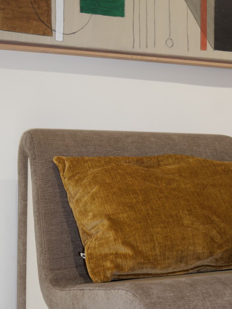 Gold decorative cushion in Italian fabric, displayed on a lounge chair